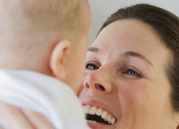 Tampak seorang ibu tertawa dan berbicara kepada bayinya