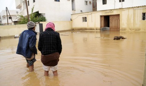  Dua orang pria berjalan di dekat rumah mereka yang terendam banjir setelah hujan lebat di Tabuk, Arab Saudi, Senin (28/1).   (Reuters/Mohamed Alhwaity)