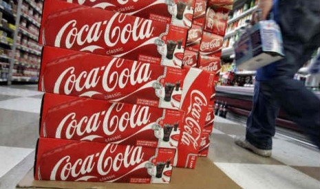 Konsumen berjalan melewati kardus produk Coca Cola di Palo Alto, California.