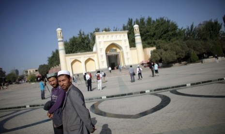 Muslim etnis Uighur berjalan di depan sebuah masjid di Kashgar, Xinjiang, Cina.