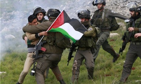 Pasukan keamanan Israel menahan seorang aktivis Palestina yang menentang pembangunan pemukiman Yahudi di Tepi Barat, Burin, Palestina, Sabtu (2/2). 