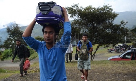 Sejumlah pengungsi korban kebakaran kios memindahkan barangnya menuju Kantor Bupati untuk kemudian ditempati di Tolikara, Papua, Jumat (24/7). 