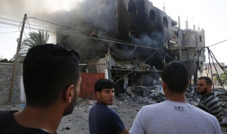 Sejumlah warga Palestina berkumpul di dekat bangunan yang hancur akibat rudal Israel di Gaza City, Jalur Gaza.