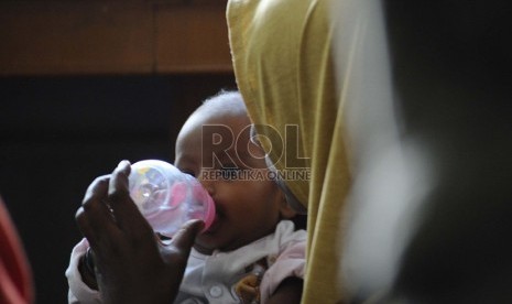  Seorang ibu memberi air minum anaknya yang berusia 4 bulan saat mengungsi di Gedung LBH Jakarta, Selasa (9/7). (Republika/ Tahta Aidilla)