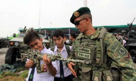 Seorang personil TNI AD menjelaskan peralatan persenjataan kepada sejumlah siswa pada sebuah pameran Alat Utama Sistem Persenjataan (Alutsista) TNI.