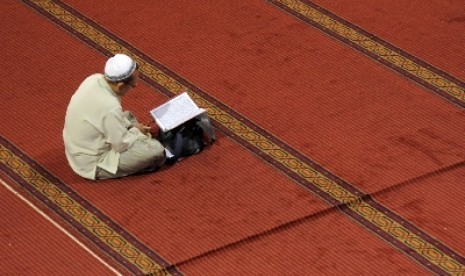 Seorang umat Muslim membaca Alquran usai melaksanakan shalat dhuha (ilustrasi).