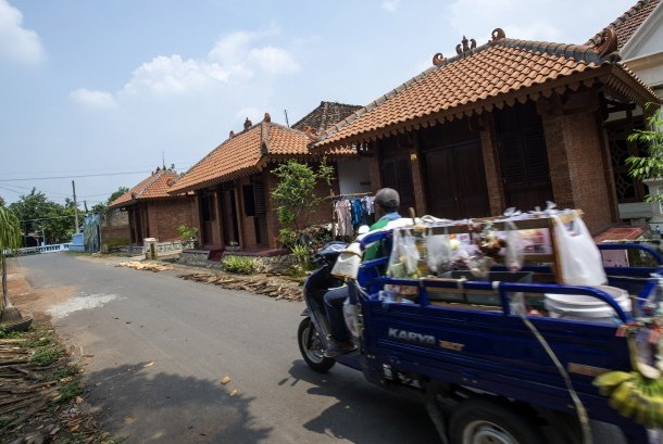 Seorang pedagang keliling melintas di depan deretan rumah bergaya arsitektur Majapahit di Desa Bejijong, Kawasan Cagar Budaya Nasional Trowulan, Mojokerto, Jawa Timur, Kamis (10/3).