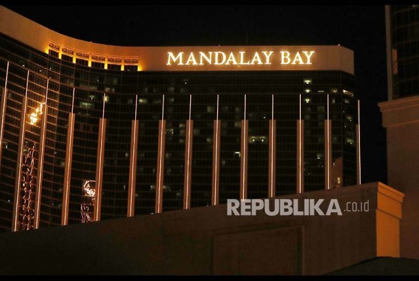 Polisi setempat berlindung dari balik mobil di dekat Mandalay Bay, Las Vegas Strip, Ahad (1/10) waktu setempat.