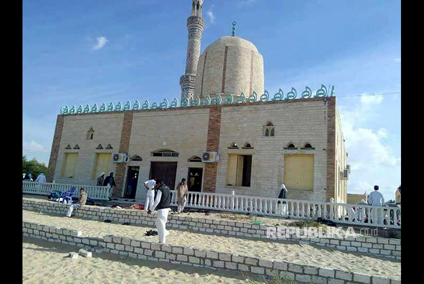 Orang-orang berjalan di luar sebuah masjid yang diserang di kota utara Arish, Semenanjung Sinai, Mesir, Jumat (24/11).