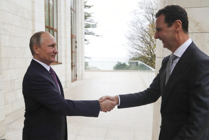 Presiden Rusia Vladimir Putin (kiri) berjabat tangan dengan Presiden Suriah Bashar Assad di kediaman Bocharov Rucheidi resor Laut Hitam Sochi, Rusia, Senin (20/11).