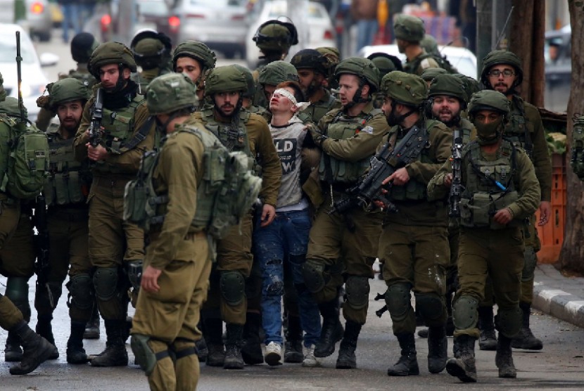 Remaja Palestina Fawzi al-Junaidi dikelilingi tentara Israel dengan mata tertutup.