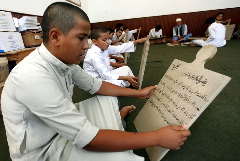 Seorang anak membaca sebuah papan tulis kayu sambil menghafal Alquran di Tripoli, Libya, Senin (23/7).   (Ismail Zitouny/Reuters)