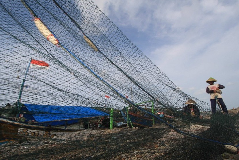 Seorang nelayan memperbaiki jaring cantrang, ilustrasi