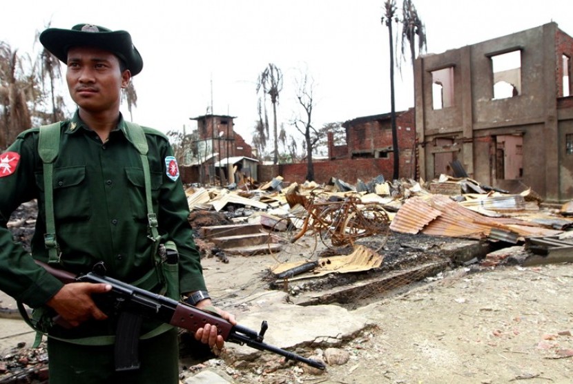 Seorang tentara Myanmar tengah berjaga di bangunan yang rusak di Sittwe, Rakhine, Myanmar.