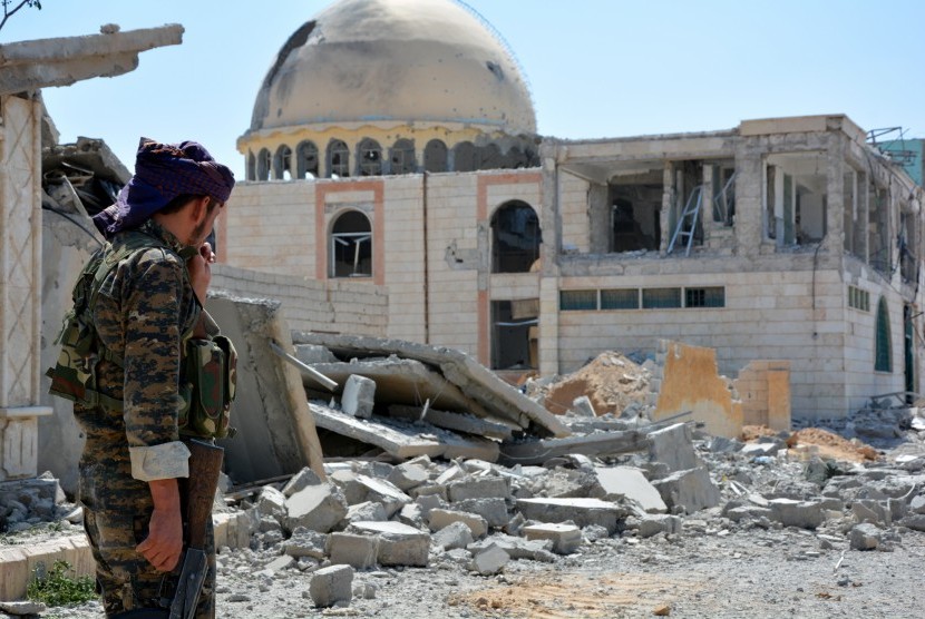 Tentara berpatroli di sebelah bangunan yang hancur di Kota Raqqa, Suriah.