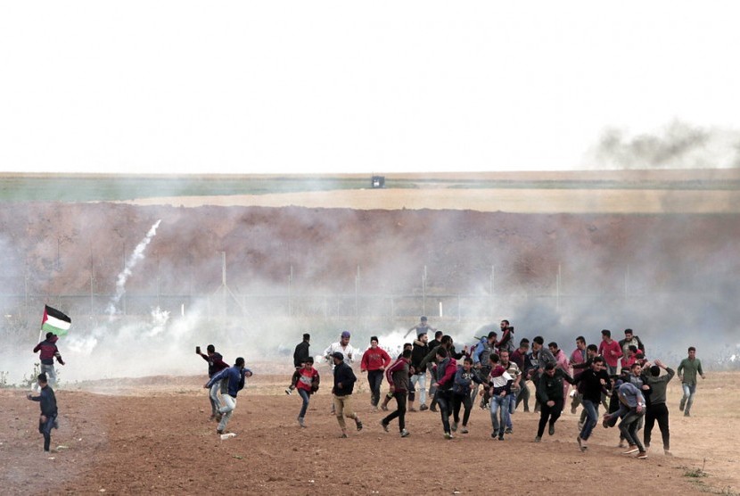 Warga Palestina berlarian saat tentara Israel menembak dengan gas air mata di Jalur Gaza, Selasa (3/4).