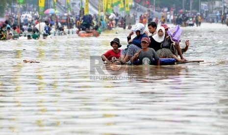   Sejumlah warga melintasi Jalan KH Abdullah Syafe'i yang terendam air dengan menggunakan rakit sederhana di Kampung Melayu Besar, Jakarta, Senin (13/1).  (Republika/Prayogi)