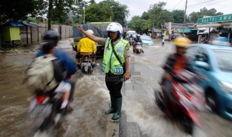   Polisi mengatur lalu lintas saat banjir menggenangi ruas jalan yang menghubungkan Ciledug dengan Cipulir, Jakarta Selatan (29/1).   (Republika/Yasin Habibi)