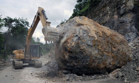  Alat berat digunakan untuk menghancurkan bongkahan batu cadas yang longsor dan menutup sebagian badan jalan di Jalan Lintas Sumatera, Kabupaten Kampar sekitar 80 kilometer dari Kota Pekanbaru, Riau, Sabtu (5/4). (Antara/FB Anggoro)