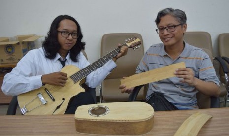                Fany Basa dan Primaditya menunjukkan gitar ciptaannya di Kamlus ITS Surabaya, Senin (11/12).