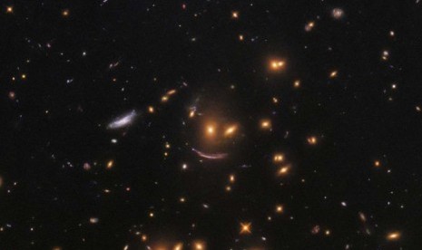 'Bintang tersenyum yang tertangkap teleskop Hubble, disebabkan oleh cahaya yang melintasi suatu objek besar dengan daya gravitasi tinggi sehingga membuatnya melengkung.