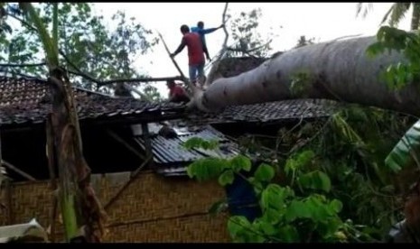  Warga berusaha memotong batang pohon yang menimpa rumah di Kecamatan Jatisrono, Wonogiri. Dok. Kodim 0728