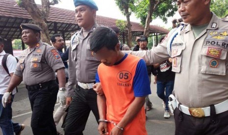 Adi Indra Purnama (baju oranye) ditangkap polisi setelah memperkosa sembilan perempuan. Enam dari sembilan korban adalah sepupunya sendiri.