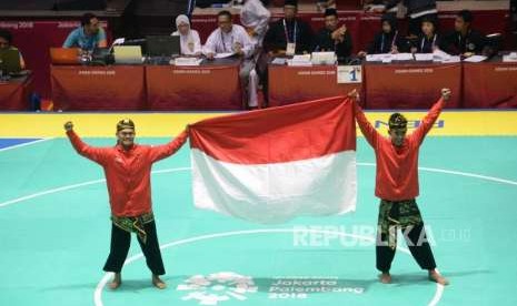 Pesilat Indoensia Yola Primadona Jampil dan Hendy membawa bendera merah putih usai final cabang pencak silat kelas artistik ganda putra Asian Games 2018 di Padepokan Pencak Silat TMII, Jakarta, Senin (27/8).