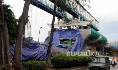 Kendaraan melintas di samping konstruksi proyek Light Rapid Transit (LRT) yang roboh di kawasan Jalan Raya Kayu Putih, Pulogadung, Jakarta Timur, Senin (22/1).