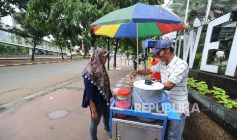 Pedagang berjualan di trotoar di kawasan Jalan Jendral Sudirman, Jakarta Pusat, Ahad (17/12).