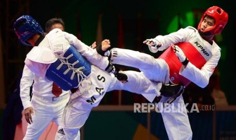 Atlet taekwondo Indonesia Dinggo Ardian (merah) melancarkan tendangan ke arah lawannya dari Malaysia Rozaimi Rozali (biru) pada babak perempat final pertandingan taekwondo kelas -80 kg pada Turnamen Invitasi Asian Games 2018 di JI Expo Kemayoran, Jakarta, Ahad (11/2).