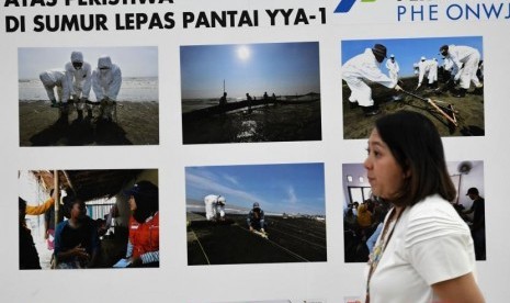 Karyawan melintasi foto-foto dokumentas penanganan kebocoran Sumur Lepas Pantai YYA-1 di Kantor Pusat Pertamina, Jakarta, Jumat (20/9/2019).