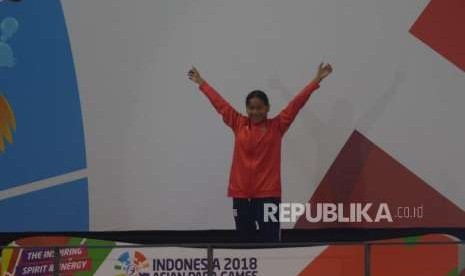 Selebrasi perenang Syuci indriani  diatas podium usai memenangkan final  Para Swim  100 Meter gaya dada di Asian Para Games, Stadion Akuatik, Jakarta, Senin (8/10).