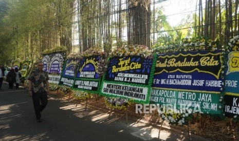 Sejumlah pelayat berjalan di depan karangan bunga ucapan belasungkawa atas wafatnya Presiden ke-3 Republik Indonesia BJ Habibie di rumah duka, kawasan Patra Kuningan, Jakarta, Kamis (13/9).