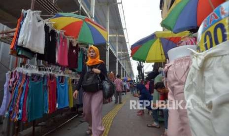 Warga melintas didekat barang dagangan para pedagang di Jalan Jatibaru, Tanah Abang, Jakarta, Kamis (27/9).