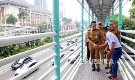 Gubernur DKI Jakarta Anies baswedan bersama Direktur Utama PT Transportasi Jakarta Budi Kaliwono melintasi jembatan penyeberangan orang (JPO) Halte Bank Indonesia di Jalan MH Thamrin, Jakarta Pusat, Selasa (4/9).