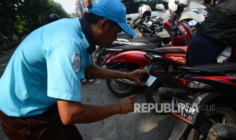 Juru parkir melakukan pemotretan nomor kendaraan bermotor untuk melakukan  pembayaran parkir di jalan danau sunter, Jakarta Utara, Jumat (29/6). (Ilustrasi)