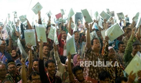  Warga mengangkat sertifikat tanah usai diserahkan oleh Presiden Joko Widodo di Sentul, Bogor, Jawa Barat, Selasa (6/3).