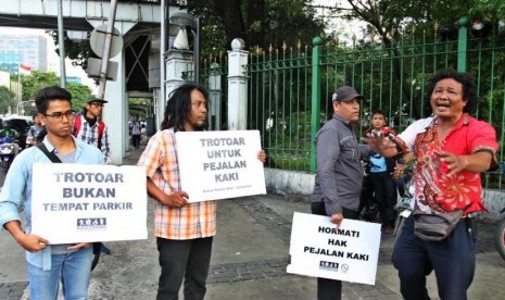 Aktivis Koalisi Pejalan Kaki (KPK) melakukan aksi di sepanjang trotoar kawasan Monas, Jakarta, Jumat (28/7). Aksi tersebut dilakukan untuk mengembalikan fungsi trotoar sebagai tempat bagi pejalan kaki yang sering diokupasi oleh kendaraan bermotor. ANTARA FOTO/ Reno Esnir/pd/17