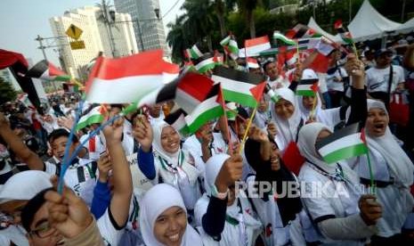 Peserta jalan santai  Walk for Peace and Humanity  mengibarkan bendera merah putih dan palestina  di kawasan car free day (CFD) Jakarta, Ahad (14/10).