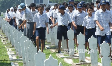 Puluhan pelajar berjalan di antara deretan makam pahlawan pada peringatan Hari Pahlawan, di Taman Makam Pahlawan Cikutra, Kota Bandung, Jumat (10/11). 