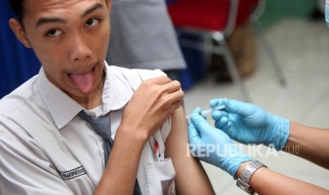 Seorang siswa berekspresi saat diimunisasi difteri pada sosialisasi komitmen pelaksaan kegiatan Outbreak Response Immunization (ORI) Difteri di Sekolah SMAN 33 Jakarta, Jalan Kamal Raya, Jakarta Barat, Senin (11/12).