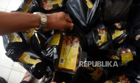 Petugas mengambil plastik untuk diberikan kepada warga saat pasar murah di Pasar Teluk Gong, Jakarta, Rabu (28/11).