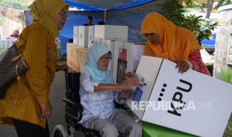 Seorang pemilih lansia dibantu petugas KPPS memasukkan surat suaranya kedalam kotak suara di TPS 65, kelurahan Sunter Jaya, Jakarta, Rabu (17/4).