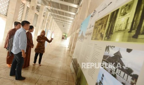 Petugas menjelaskan tulisan mengenai masjid-masjid bersejarah di Indonesia kepada wisatawan di Masjid Istiqlal, Jakarta, Senin (5/11).