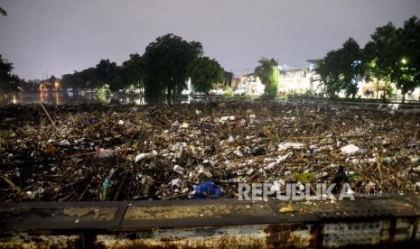 Warga melihat sampah yang terbawa luapan air sungai ciliwung di Jembatan Kampung Melayu, Jakarta, Senin (5/2) malam.