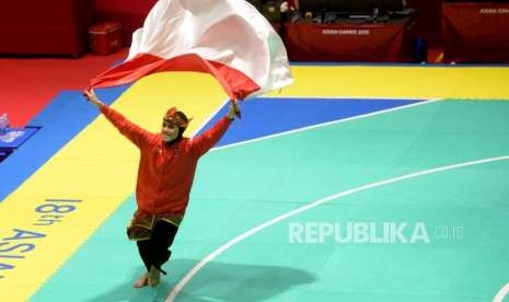 Pesilat Indoensia Puspa Arumsari berlari dengan membawa bendera merah putih usai beraksi pada final cabang pencak silat kelas artistik tunggal putri Asian Games 2018 di Padepokan Pencak Silat TMII, Jakarta, Senin (27/8).