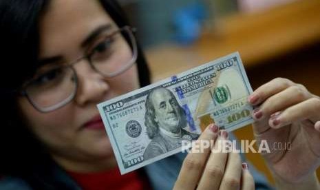 Petugas memeriksa kondisi dolar Amerika Serikat di gerai penukaran mata uang asing di Jakarta, Selasa (2/10).