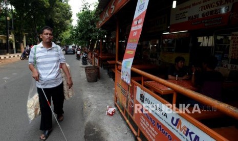 Robin (41) penjual kerupuk penyandang tuna netra berjalan untuk menjual kerupuknya di kawasan Blok S, Kebayoran Baru, Jakarta Selatan, Kamis (18/10).