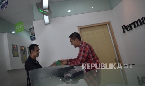 Karyawan melayani transaksi nasabah di Permata Bank Jakarta, Jumat (9/11).